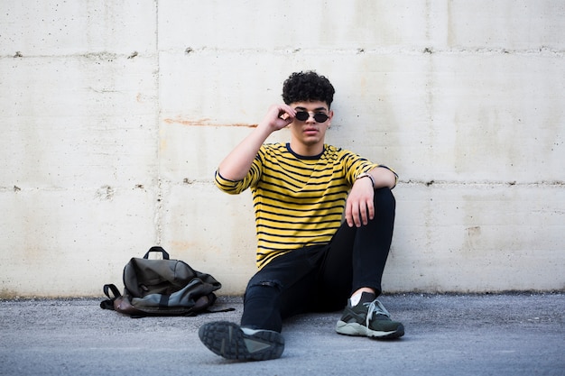 Ethnique jeune homme avec une coiffure cool assis sur l&#39;asphalte