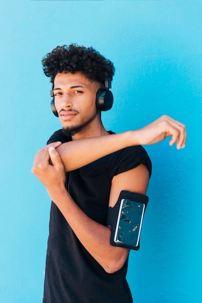 Ethnique mâle qui s&#39;étend et écoute de la musique avec un étui de téléphone sur le bras