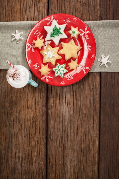 Photo gratuite Étoile biscuits en forme sur une plaque rouge et tasse de crème