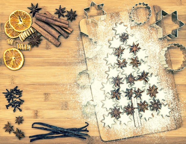 Étoiles et épices de cannelle de biscuit de noël sur le fond en bois. gousses de vanille, clous de girofle, anis étoilé et cannelle. image tonique de style vintage