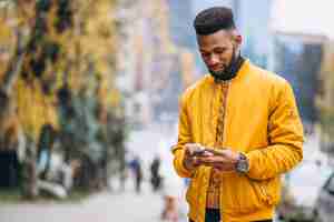 Photo gratuite Étudiant afro-américain marchant dans la rue et parler au téléphone