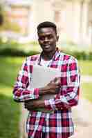 Photo gratuite Étudiant afro-américain avec ordinateur portable dans la journée ensoleillée sur la rue de la ville