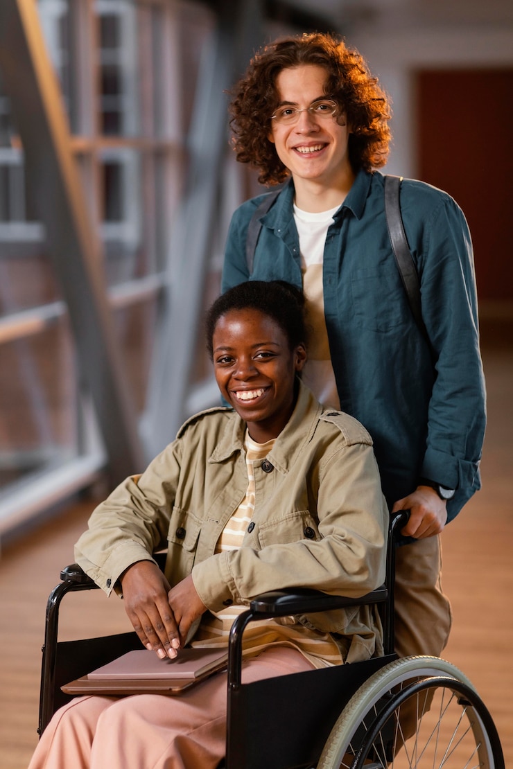 Photo gratuit étudiant aidant un collègue en fauteuil roulant