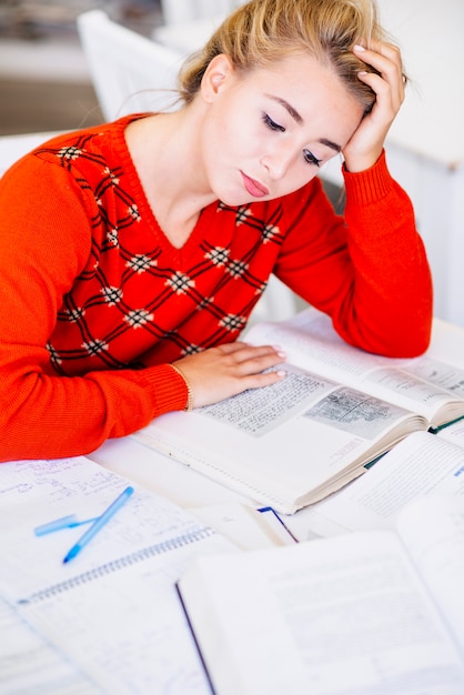 Photo gratuite Étudiant assis avec un livre à table