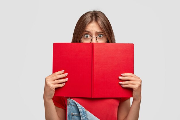 Un étudiant choqué et stressant répète sa réponse, se cache derrière un livre