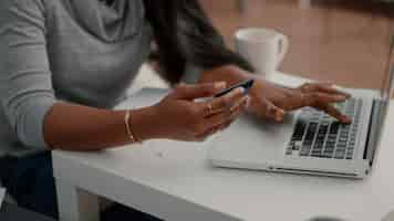 Photo gratuite Étudiant noir tenant une carte de crédit dans les mains faisant des transactions électroniques à la recherche d'une boutique en ligne