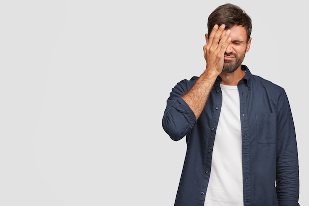 étudiant stressant posant contre le mur blanc