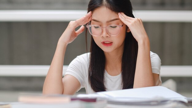 Une étudiante asiatique lit des livres dans une bibliothèque à l'université