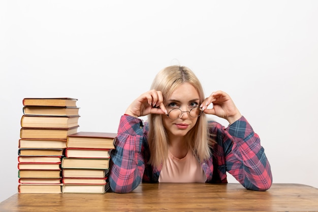 étudiante assise avec différents livres sur blanc