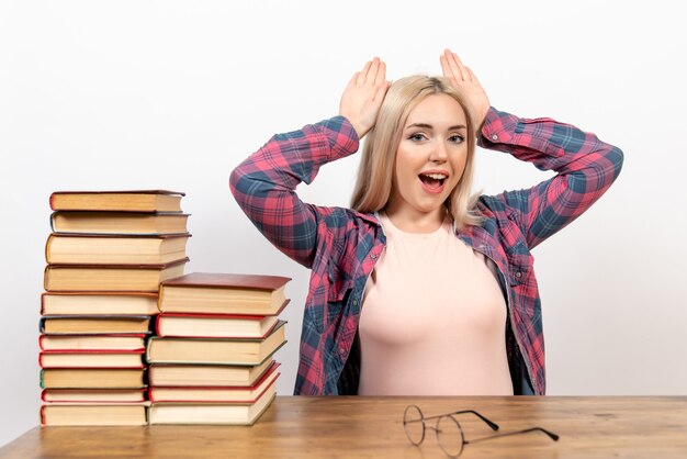 étudiante assise avec des livres et posant sur blanc