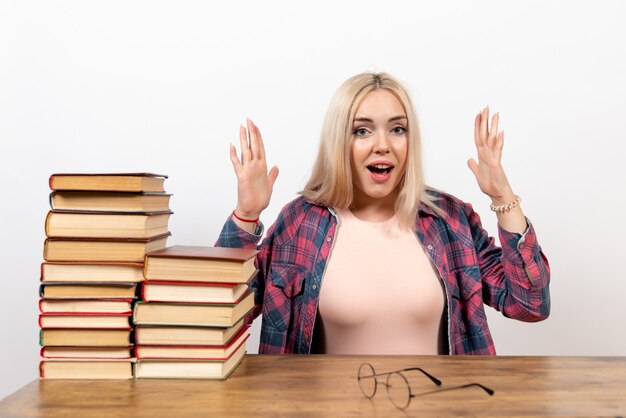 étudiante assise avec des livres et posant sur blanc