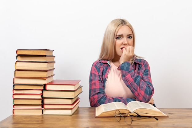 étudiante assise avec des livres et posant sur blanc