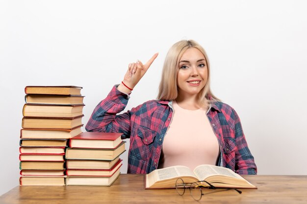 étudiante assise avec des livres et posant sur blanc