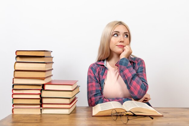 étudiante assise avec des livres et posant la pensée sur blanc