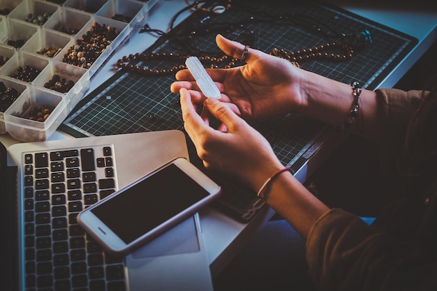 Photo gratuite une étudiante créative tient du cristal de quartz dans les mains tout en étant assise sur son lieu de travail.