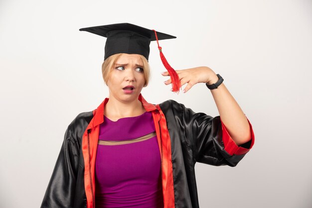 étudiante diplômée en robe regardant de côté sur blanc.