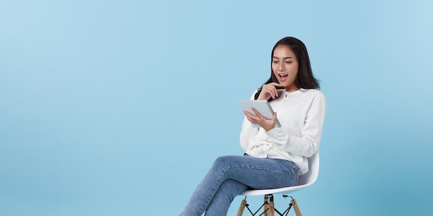 étudiante intéressée à penser qu'elle tient un cahier assis sur une chaise blanche