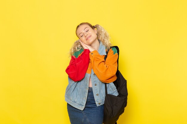 étudiante jeune dans des vêtements modernes se présentant comme doux dormir sur jaune