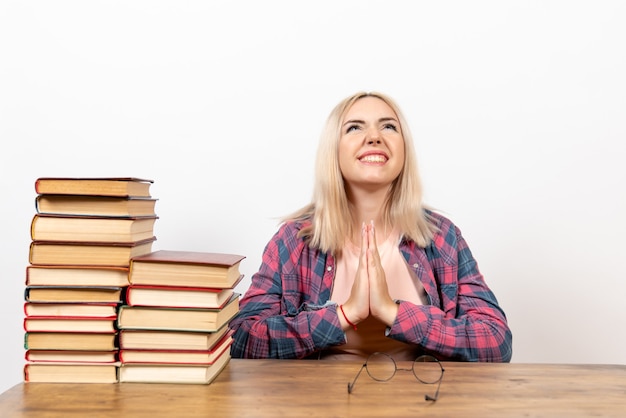 Photo gratuite Étudiante juste assise avec des livres sur blanc