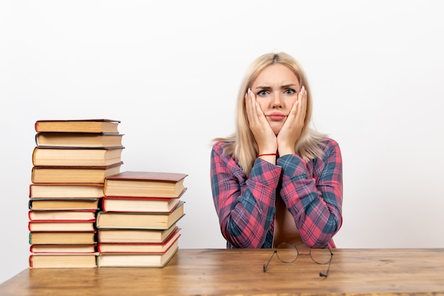 étudiante juste assise avec des livres sur blanc