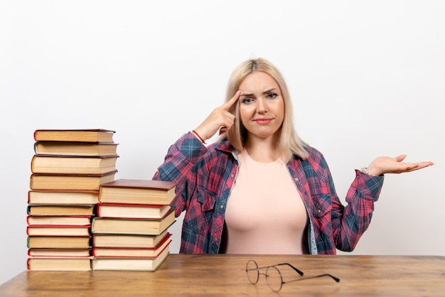 étudiante juste assise avec des livres sur blanc