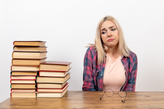 étudiante juste assise avec des livres déprimés sur blanc