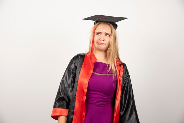 étudiante en robe faisant un visage idiot sur blanc.