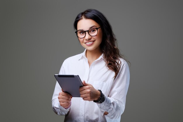 L'étudiante séduisante détient une tablette PC. Isolé sur fond gris.