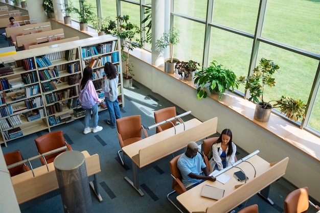 Photo gratuite Étudiants à angle élevé apprenant à la bibliothèque