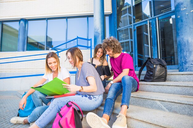 Les étudiants lisant des manuels sur les marches près de l&#39;université