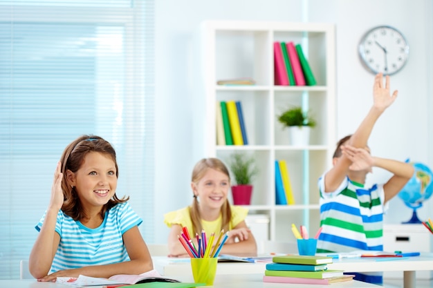 Les étudiants qui élèvent leurs mains dans la classe