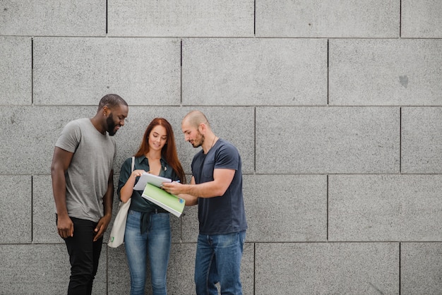 Photo gratuite Étudiants tenant des cahiers debout, souriant