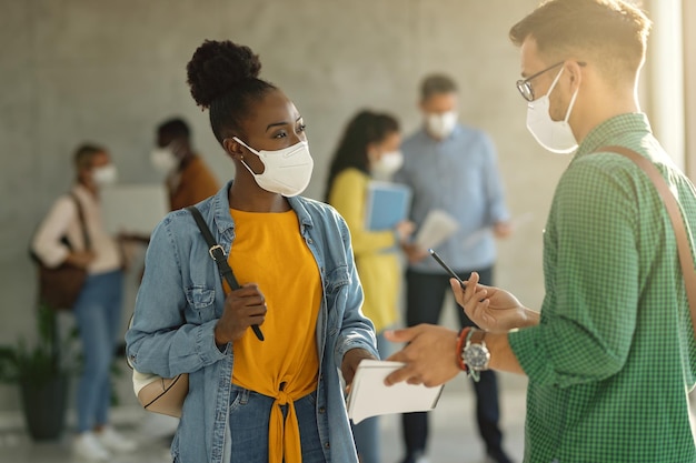 Photo gratuite Étudiants universitaires avec des masques protecteurs parlant dans un couloir