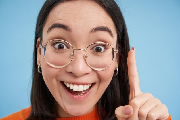 Eureka portrait en gros plan d'une femme coréenne excitée dans des verres montre qu'un doigt a une idée se tient au-dessus