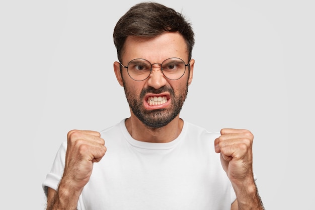 Photo gratuite un européen furieux en colère serre les dents et les poings de rage, tente de contrôler ses émotions négatives