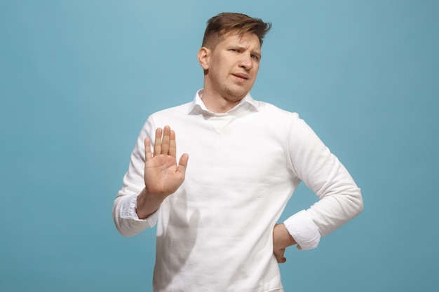 Ew. C'est tellement dégoûtant. Jeune homme avec une expression dégoûtée repoussant quelque chose. Concept de dégoût. Jeune homme émotionnel. Émotions humaines, concept d'expression faciale. Studio. Isolé sur la couleur bleue à la mode