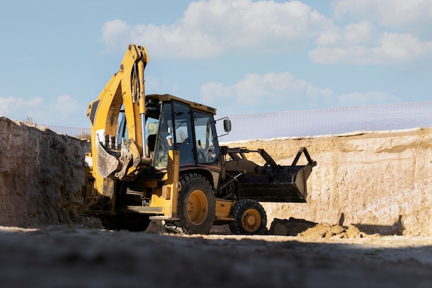 Excavatrice creusant dans le sol à la lumière du jour