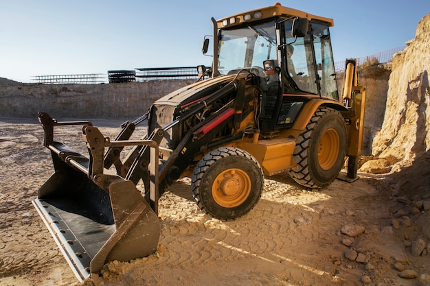 Excavatrice creusant dans le sol à la lumière du jour