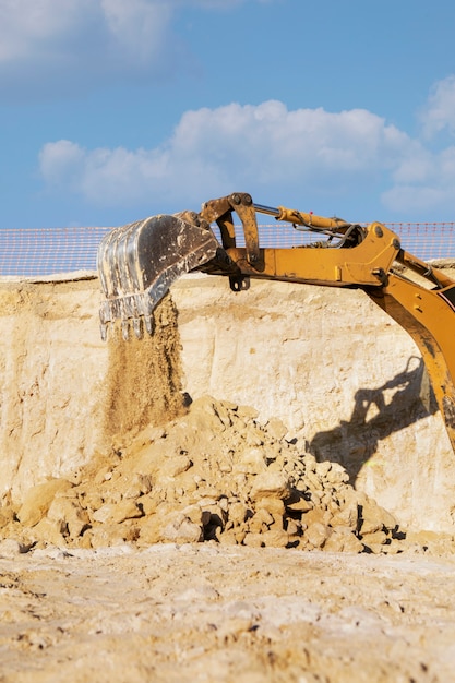 Excavatrice creusant dans le sol à la lumière du jour