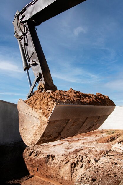 Une excavatrice creuse dans le sol à la lumière du jour