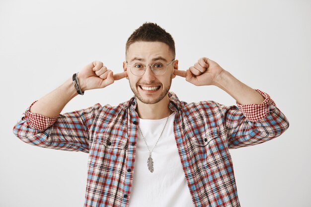 Excité beau jeune homme avec des lunettes posant