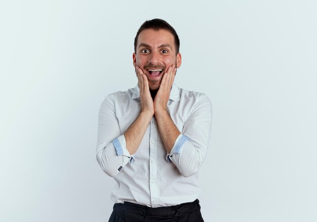 Excité bel homme met les mains sur le visage isolé sur un mur blanc