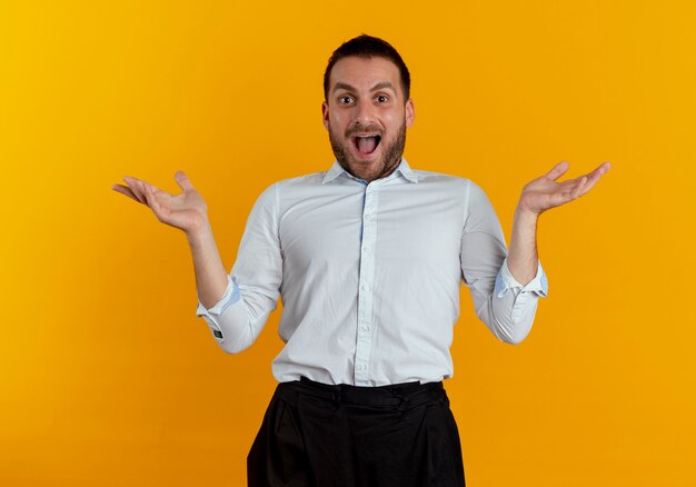 Excité bel homme se tient avec les mains ouvertes isolé sur mur orange