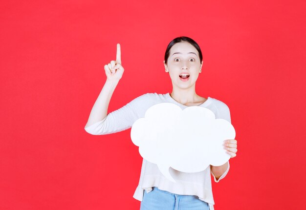 Excité belle femme tenant une bulle de dialogue avec une forme de nuage