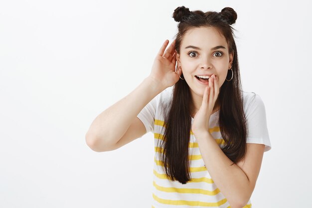 Excité élégant jeune femme posant contre le mur blanc