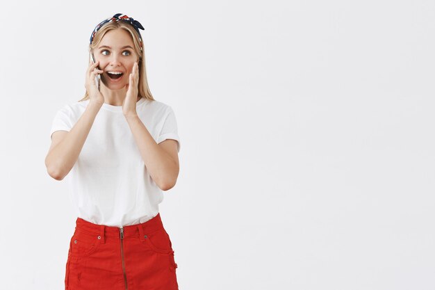 Excité femme heureuse parler au téléphone et à la surprise