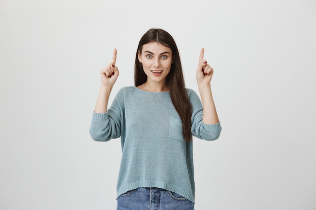 Excité femme heureuse pointant les doigts vers le haut, étant étonné