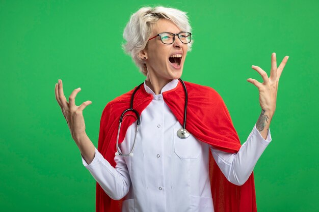 Excité femme de super-héros slave en uniforme de médecin avec cape rouge et stéthoscope à lunettes optiques