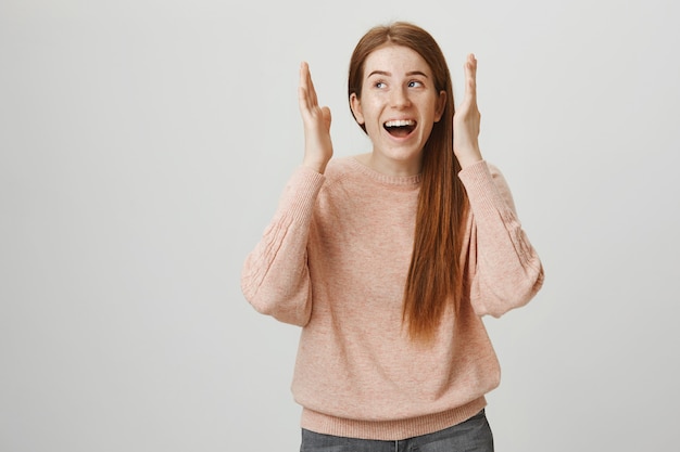 Excité fille rousse heureuse ouvrir les yeux et détourner le regard enthousiaste