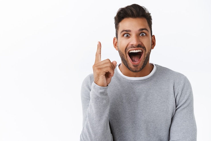 Photo gratuit excité et heureux, un beau mec réfléchi a une excellente idée de ce qu'il faut acheter pour la saint-valentin, a trouvé une variante parfaite en magasin ou en faisant des achats en ligne, levez l'index dans le geste eurêka, souriant étonné